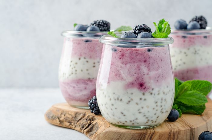 Clear, glass pots of yogurt with chia seeds and blueberries on top.